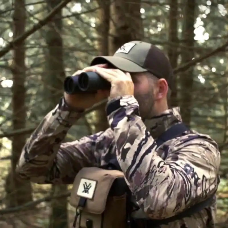 Man in camouflage holding binoculars.